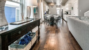 A spacious kitchen with a central island, white cabinets, and a chandelier. - Carlton Landing! Charming Cottage on boardwalk! (Carlton Landing)