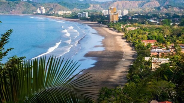 Vista costera con playa, edificios y colinas.