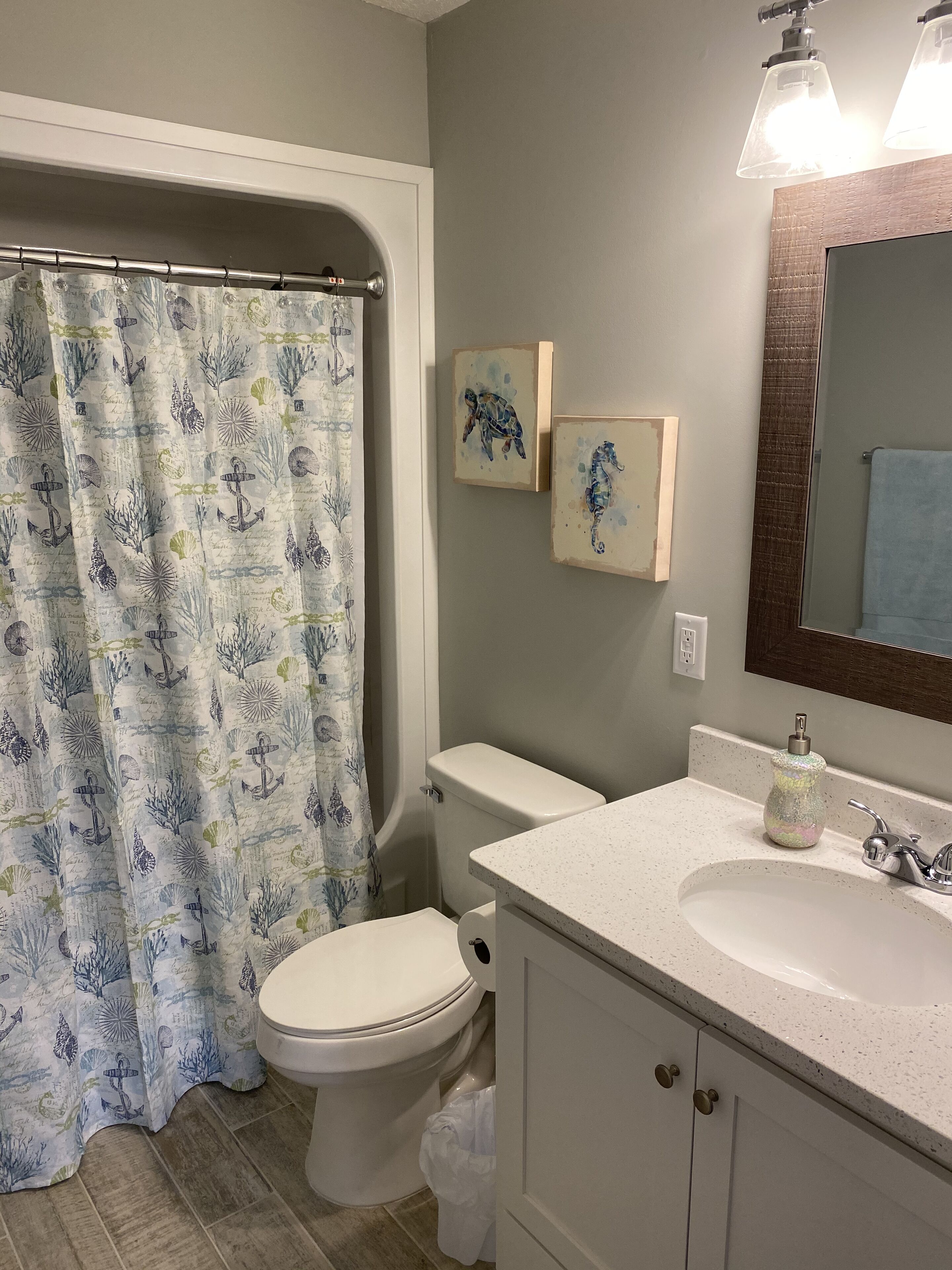 A bathroom with a shower curtain, toilet, sink, and a mirror.
