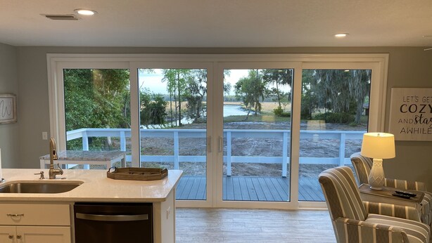 A kitchen with a large window, a dining area with striped chairs, and a sign on the wall.