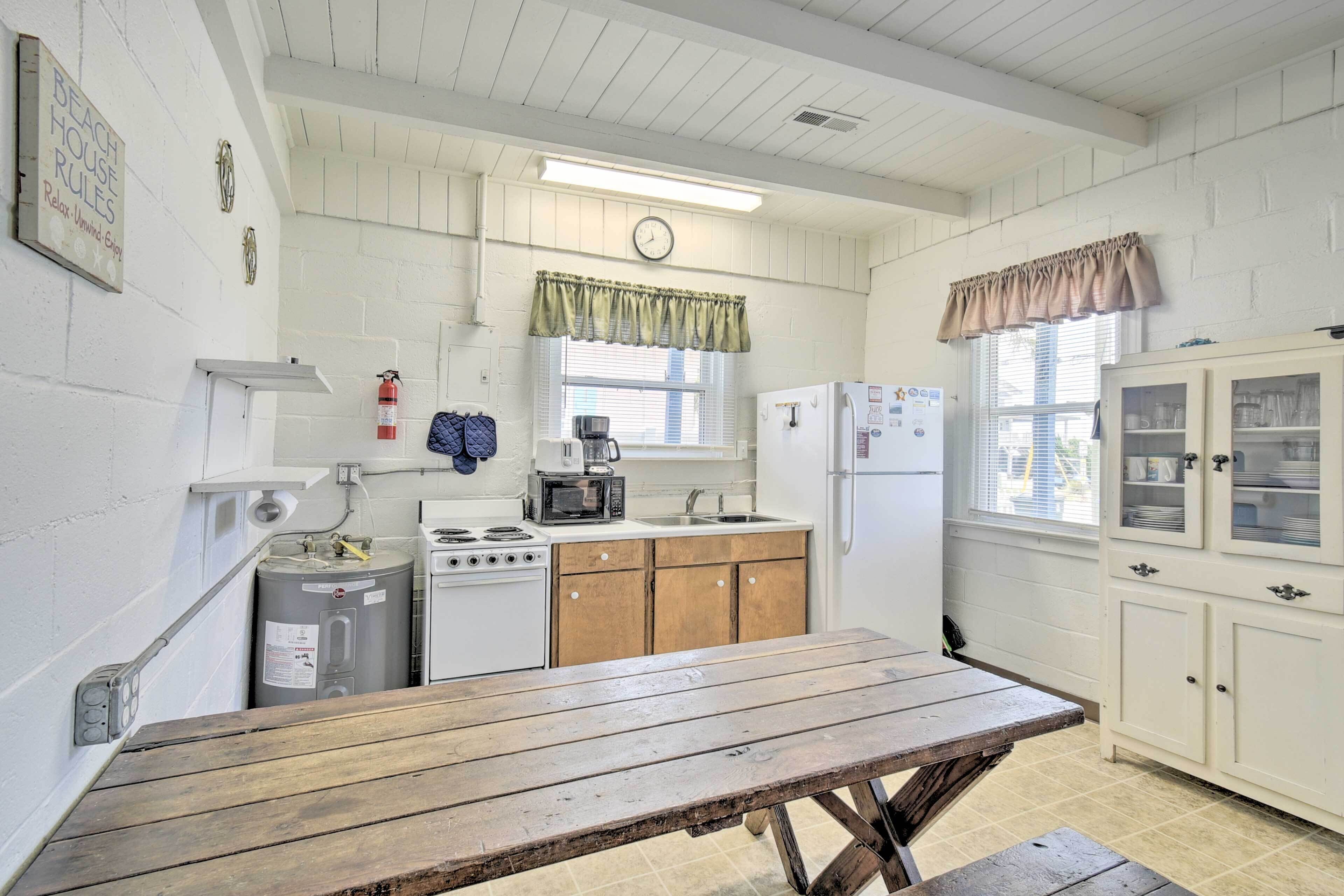 A compact kitchen with a stove, microwave, sink, and cabinets.