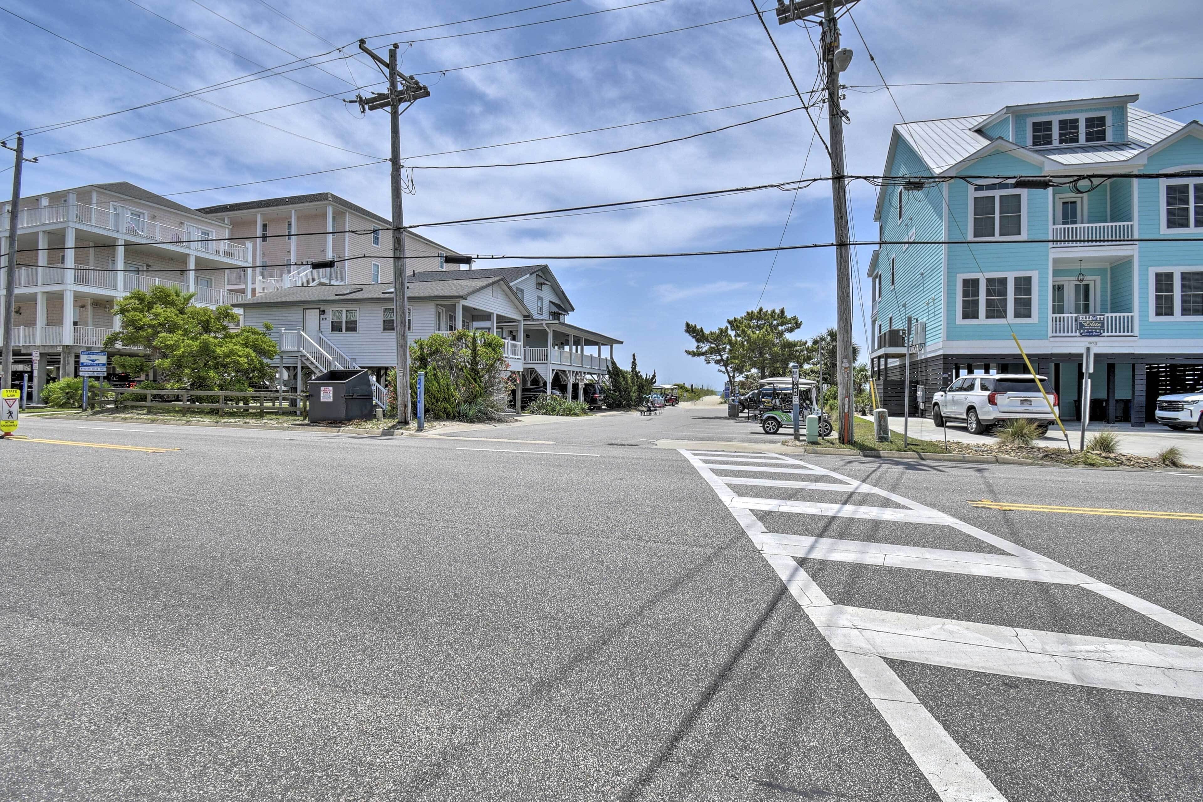 A street view with a crosswalk, buildings, and parked cars.