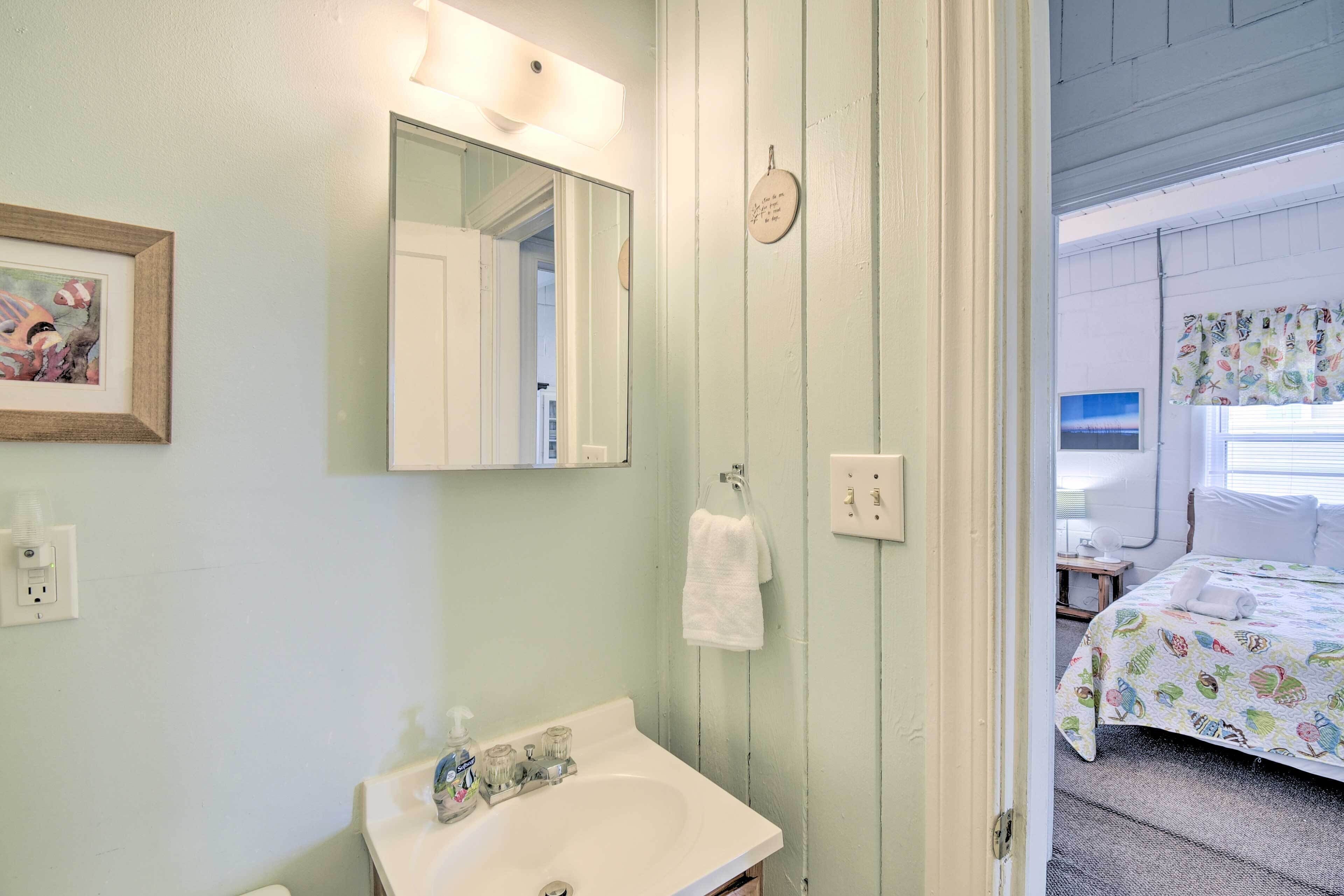 A bathroom with a sink, mirror, and towel rack.
