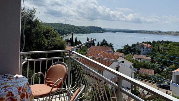 A balcony with a view of a lake, surrounded by trees and buildings. - Apartment Gordana 1 with sea view (Omisalj)