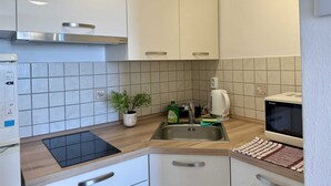 A modern kitchen with white cabinets, a stainless steel sink, a microwave, and a built-in oven.