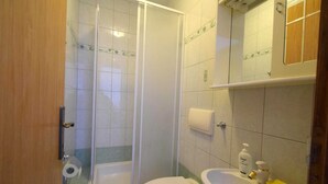 A bathroom with a shower, toilet, and sink.