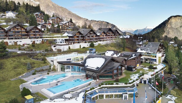 Een bergresort met meerdere chalets, een zwembad en een skilift.