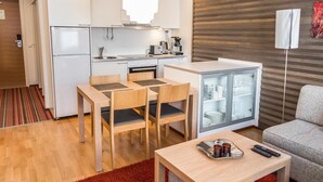 Een compacte keuken met een eethoek, een koelkast, een koffieapparaat en een glazen kast.