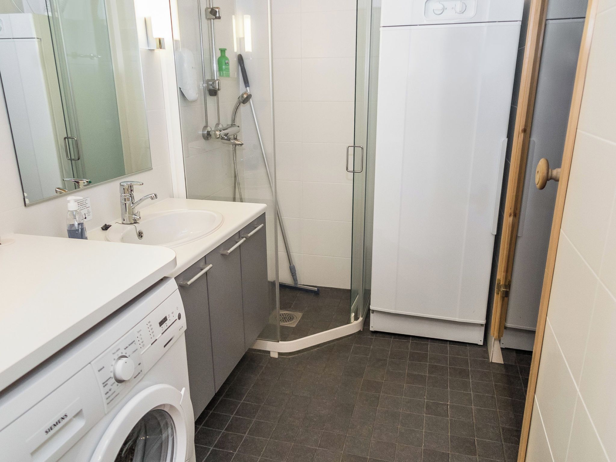 Ein modernes Badezimmer mit Dusche, Waschbecken und Waschmaschine.
