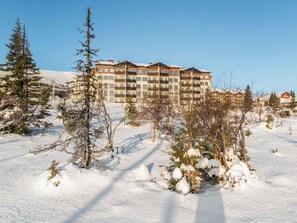 A multi-story hotel with balconies, surrounded by snow-covered ground and trees.