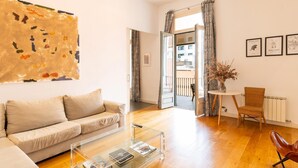 Uma sala de estar moderna com sofá, mesa de centro de vidro e vista para o exterior.