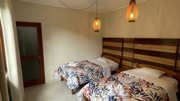 Habitación de hotel con dos camas individuales, cabecero de madera y dos lámparas colgantes.