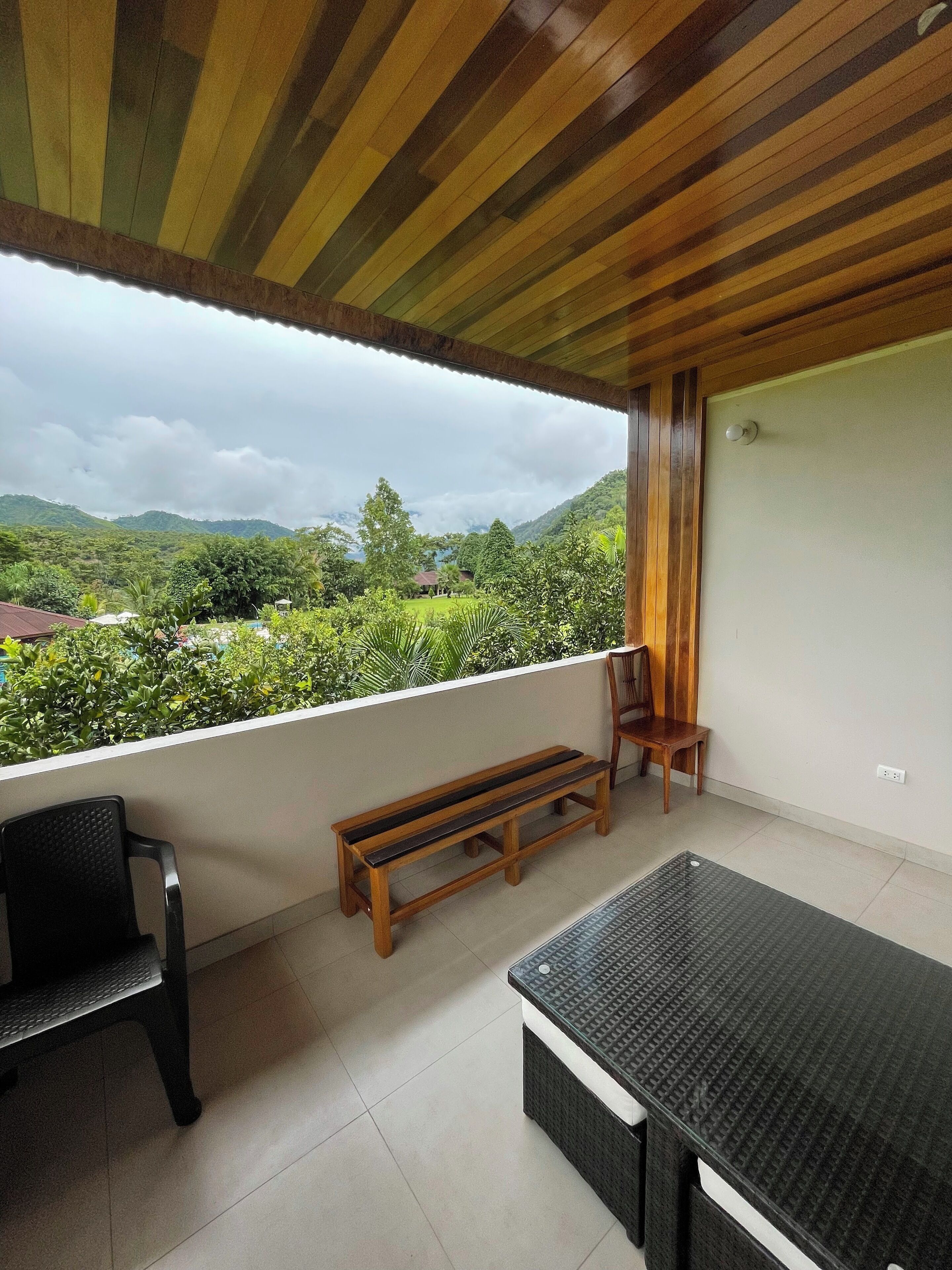 Un balcon doté d’un plafond en bois, d’un banc, d’une table et d’une chaise.