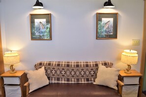 A cozy room with a brown leather sofa, two matching lamps, and two framed pictures on the wall. - Little Big Fish (Packwood)