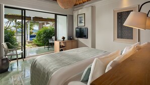 Une chambre moderne avec un grand lit, un bureau avec une télévision et un balcon offrant une vue sur la mer.