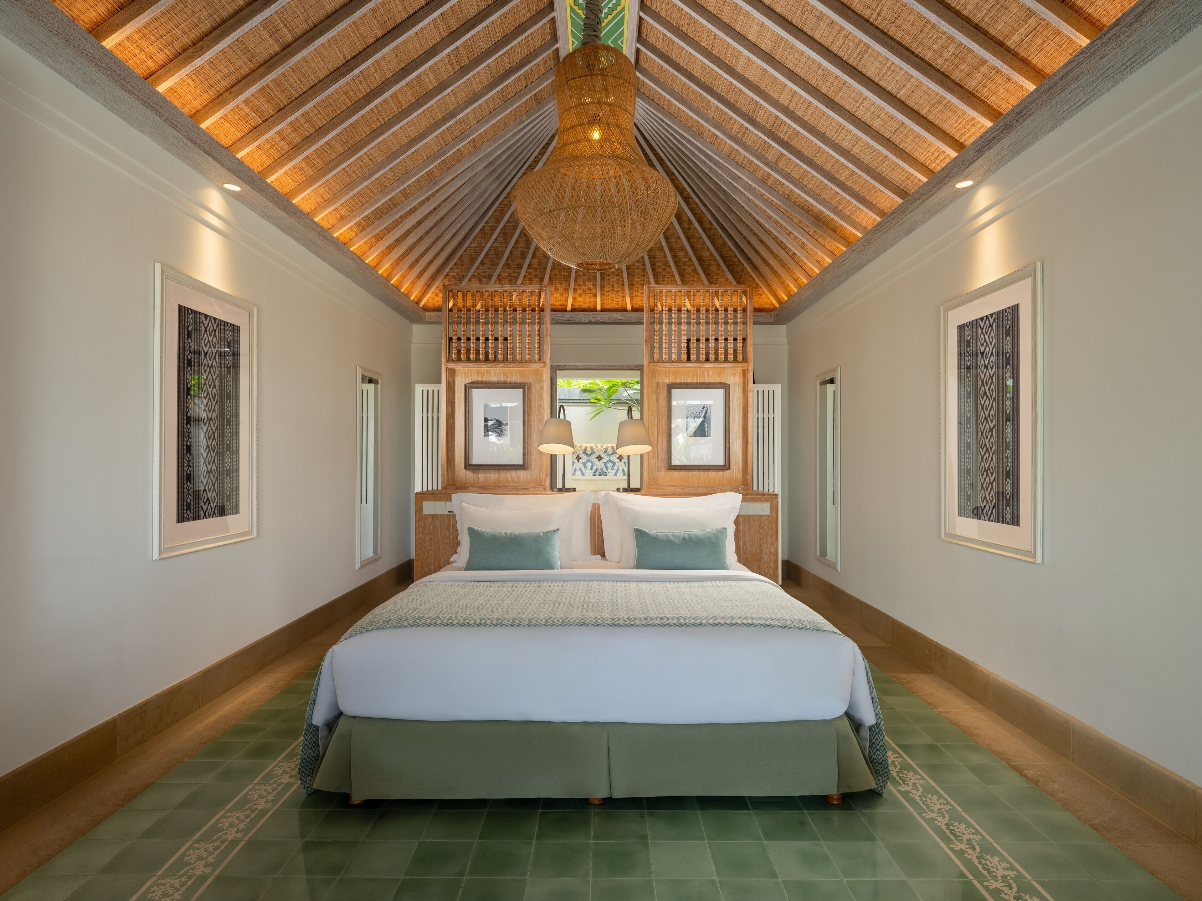 A spacious bedroom with a large bed, a wooden ceiling, and framed artwork on the walls.