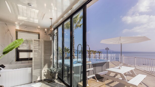 A modern room with a large glass wall, a private pool, and a patio with a table and chairs. - Lim Sea Side Poolvilla Pension (Namhae)