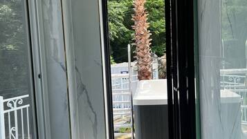 En modern inredning med ett stort fönster, ett marmorgolv och utsikt över en trädgård.