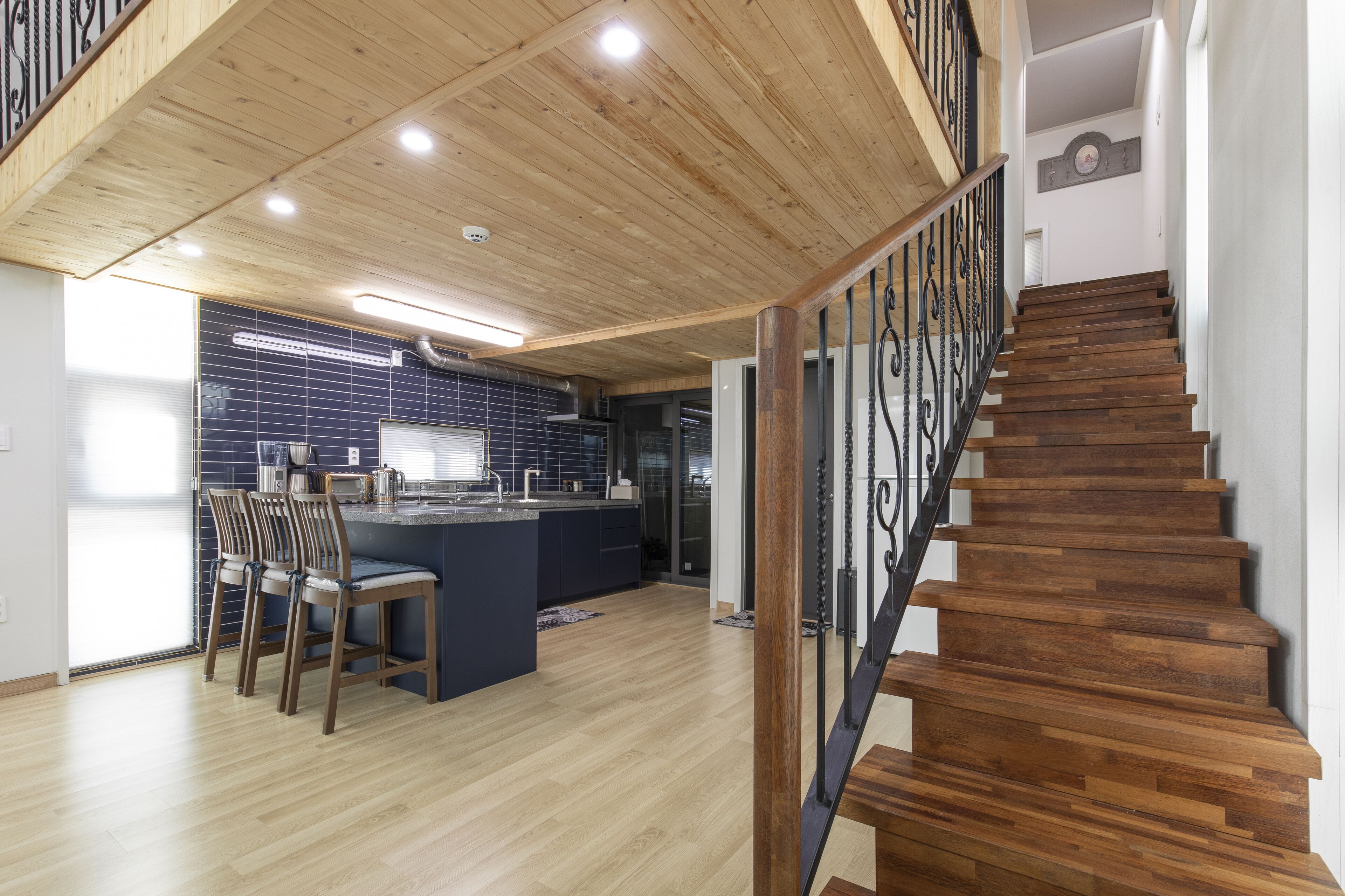 Eine moderne Küche mit einer zentralen Kochinsel, Holzboden und einer Treppe mit Metallgeländer.