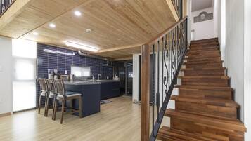 Eine moderne Küche mit einer zentralen Kochinsel, Holzboden und einer Treppe mit Metallgeländer.