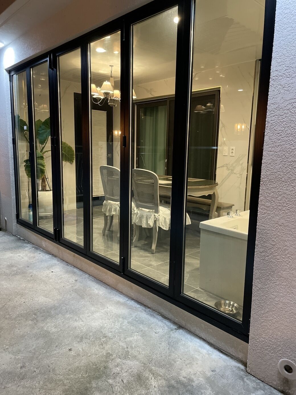 A modern interior with a dining area, a kitchen, and a bathroom visible through large glass doors.