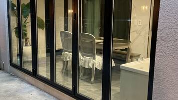 A modern interior with a dining area, a kitchen, and a bathroom visible through large glass doors.