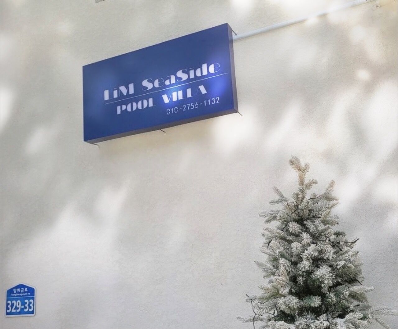 A blue sign for Limi Seaside Pool Villa with a contact number.