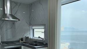 A modern kitchen with a large window, a built-in stove, and a stainless steel range hood. - Lim Sea Side Poolvilla Pension (Namhae)