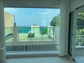 Un balcón con vistas al océano, una mesa y una silla.