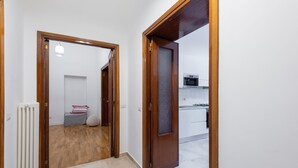 A hallway with a wooden door leading to a kitchen area. - SPANISH STEPS 3 BEDROOM PRESTIGIOUS HOME (Roma)