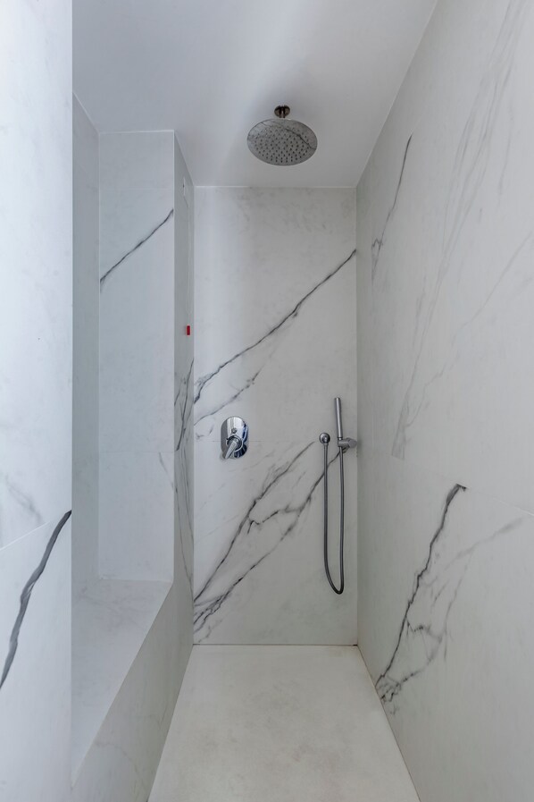 A modern shower with a handheld showerhead and a wall-mounted faucet.