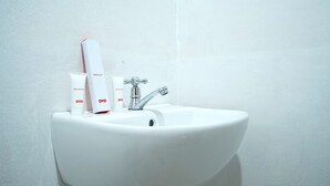 Een witte wastafel met een chroomkraan en een witte muur.