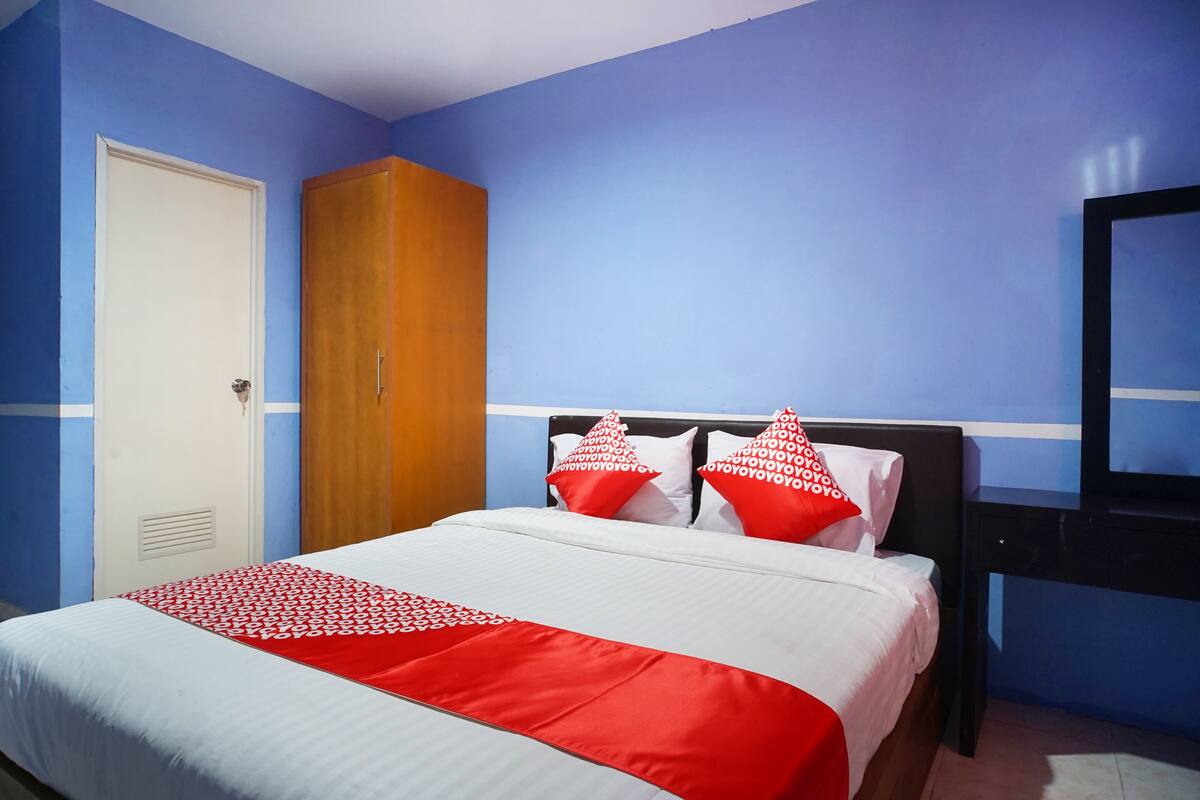 Een hotelkamer met een bed, een kledingkast, een televisie en een deur.