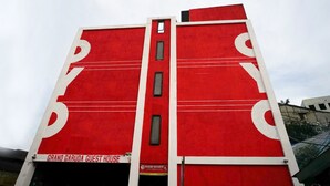 Een rood gebouw met een bord waarop staat: Grand Garuda Guest House.