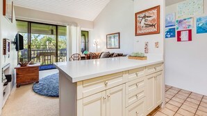 A modern kitchen with a large island, white cabinetry, and a dining area with a table and chairs.