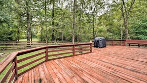 Une terrasse en bois dotée de rampes, entourée d’une zone boisée.
