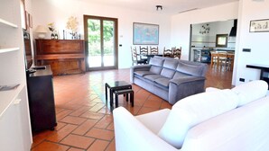 A spacious living area with a grey sofa, a white sofa, and a small table. There is a wooden cabinet and a map on the wall.