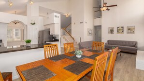 A spacious living area with a dining table, wooden chairs, a gray sofa, and a kitchen in the background. - Scottsdale Oasis! 5 BR, 7 beds, pool, 3000+ sq ft - near Mayo Clinic Hospital (Scottsdale)
