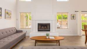 A spacious living room with a fireplace, a sofa, a coffee table, and two windows with blinds. - Scottsdale Oasis! 5 BR, 7 beds, pool, 3000+ sq ft - near Mayo Clinic Hospital (Scottsdale)