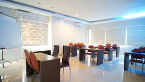 A conference room with a long table, multiple chairs, and a projector screen.
