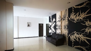 A spacious lobby with a black leather sofa, a large wall mural, and a framed picture on the wall.