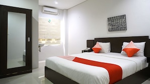A hotel room with a large bed, a bedside table with a phone, and a wall-mounted artwork.