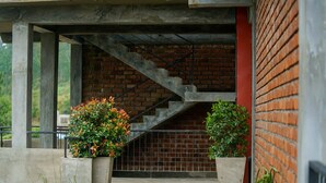 Una escalera que conduce a un muro de ladrillo, con macetas de concreto y una barandilla metálica.