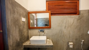 Un baño con un lavamanos rectangular, un espejo y una ventana de madera.