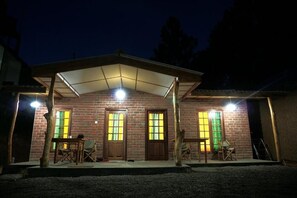 A brick house with a covered porch, two doors, and a table with chairs. - Rawana Den (Ella)
