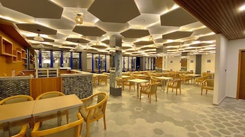 Un restaurante espacioso con paneles hexagonales en el techo, mesas y sillas de madera.