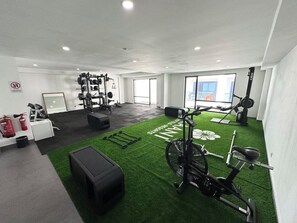 A gym with exercise equipment, a stationary bike, and a green artificial turf area. - Kaani Palm Beach (Maafushi)