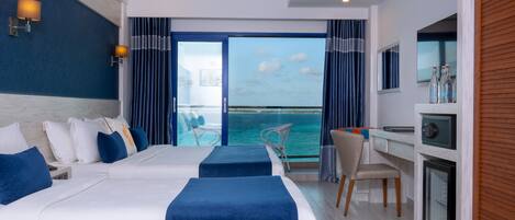 Habitación de hotel con dos camas, un escritorio, una silla, un televisor y vista al mar.