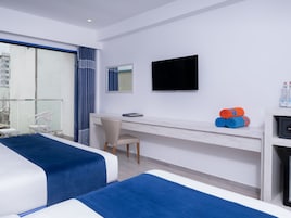 Habitación de hotel con dos camas, un escritorio, una silla, un televisor y vistas a la ciudad.