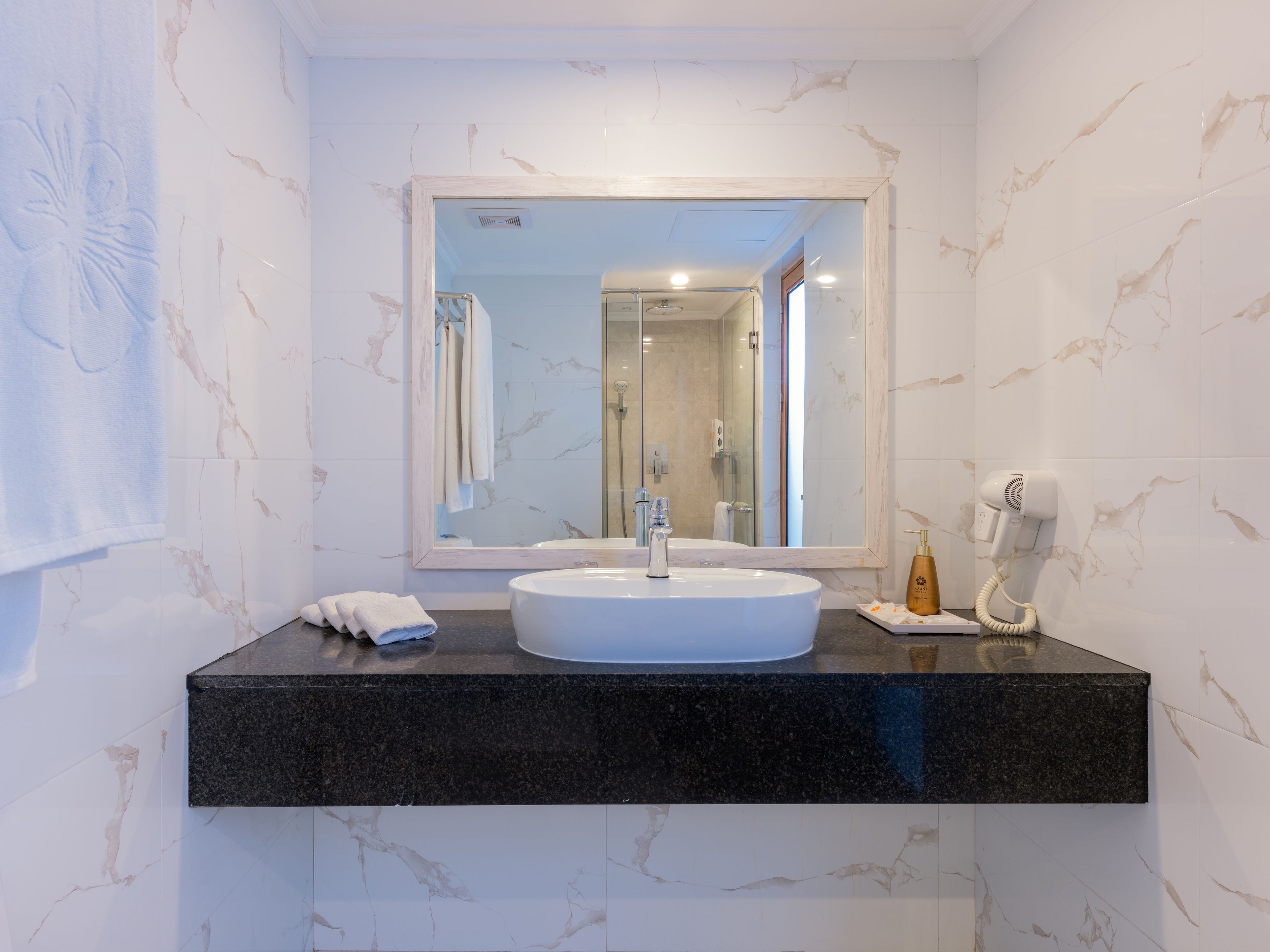 A bathroom with a white sink, a mirror, and a hairdryer on the counter.